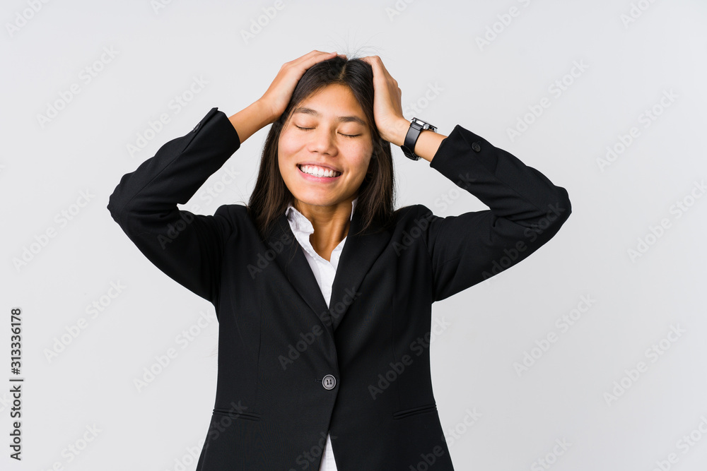 Young asian business woman laughs joyfully keeping hands on head. Happiness concept. Young asian business woman laughs joyfully keeping hands on head. Happiness concept.