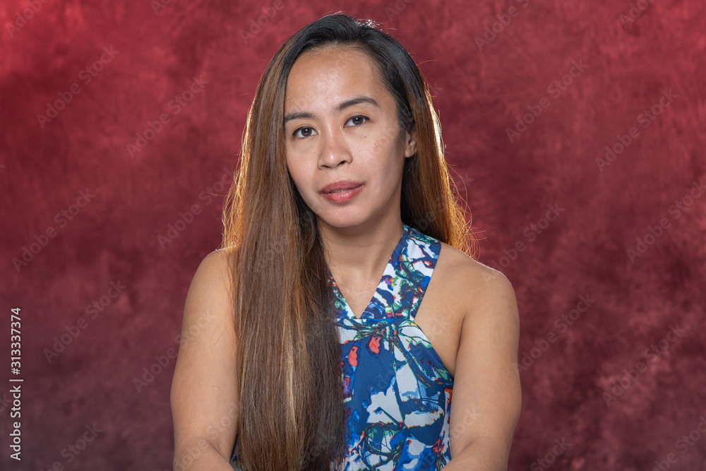 Young Filipina woman posing for studio headshots. Backlit on red and blue background Young Filipina woman posing for studio headshots. Backlit on red and blue background