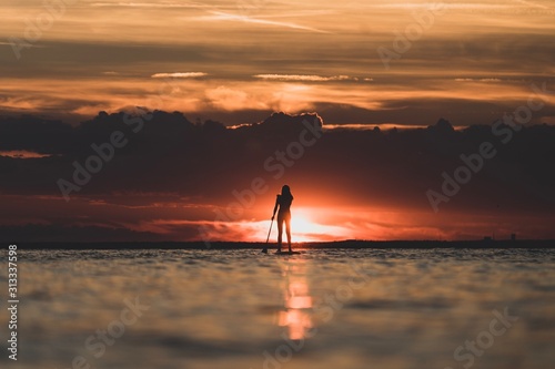 Girl paddlesurfing in sunset. © Ludvig