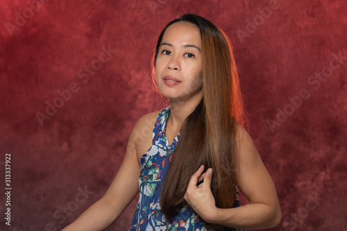 Young Filipina woman posing for studio headshots. Backlit on red and blue background