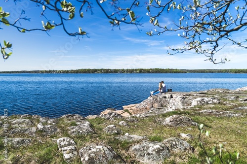 Young couple sitting beside the water with trees in the foreground. 