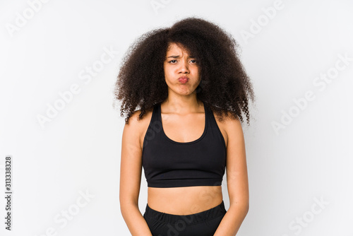 Young african american sporty woman blows cheeks, has tired expression. Facial expression concept.