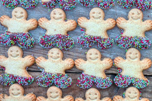 Symbol of Merry Christmas and Happy New Year: Set of smiling gingerbread man. Sweet holiday cookies isolated on wood background