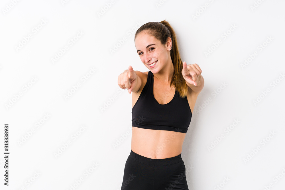 Young caucasian fitness woman posing in a white background cheerful smiles pointing to front. Young caucasian fitness woman posing in a white background cheerful smiles pointing to front.