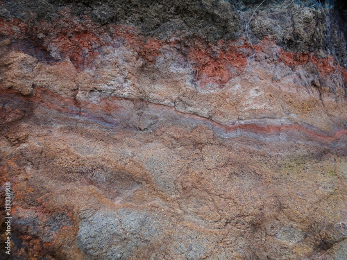 Mottled color of purples and grays and reds show in this picture of a dirt cliff alongside a road in Maui.