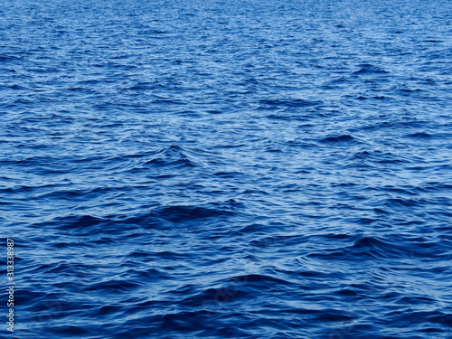 Background texture of vivid blue ocean water with ripples and waves.