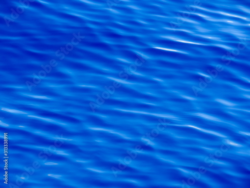 Background texture of vivid blue ocean water with ripples and waves.