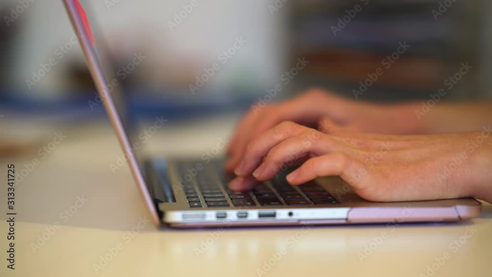 junge Frau tippt auf Laptop Tastatur im Büro close-up