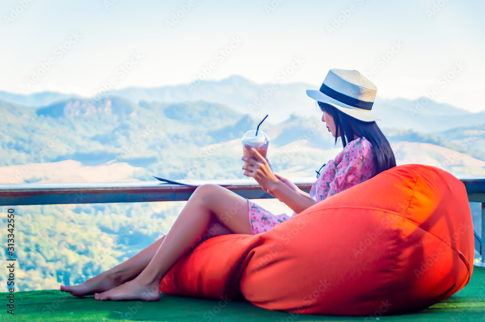 Enjoying time at balcony. Beautiful young woman drinking ice tea and use handphone. Enjoying time at balcony. Beautiful young woman drinking ice tea and use handphone.