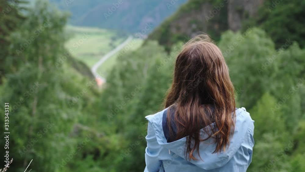 Dreamy girl sits on a background of mountains with flying hair. Back of view. slow motion Dreamy girl sits on a background of mountains with flying hair. Back of view. slow motion