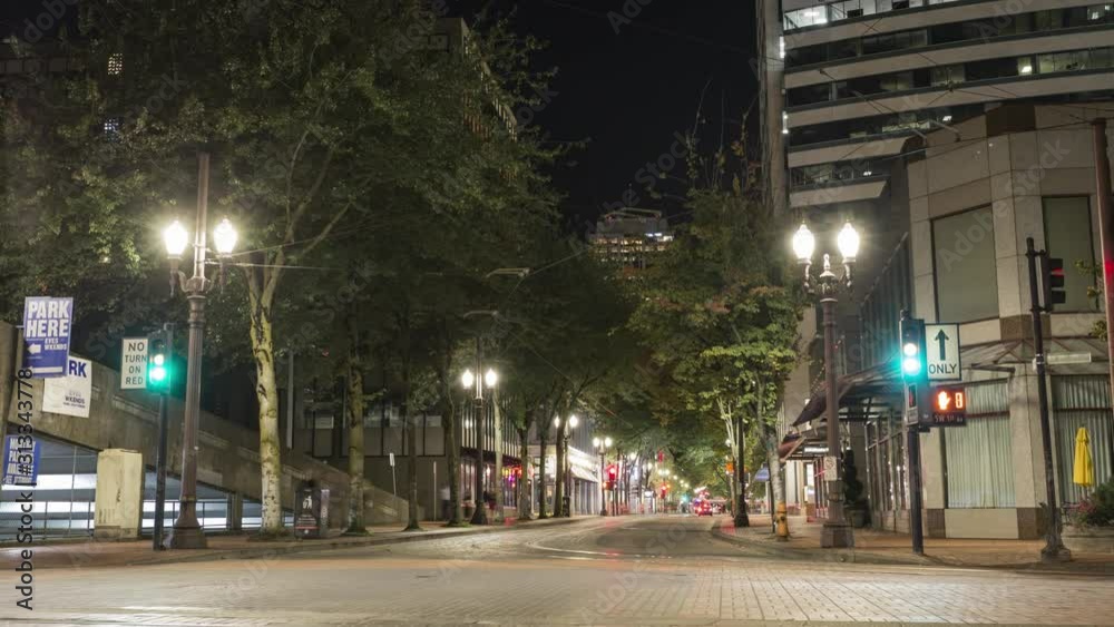 Portland street timelapse in downtown Portland, Oregon as cars, buses and MAX trains cross the intersection at night.