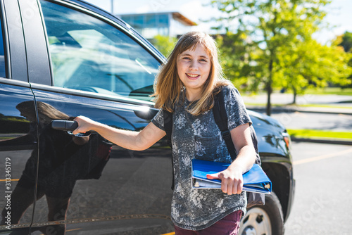 Φωτογραφία Happy teenage girl standing beside a car/suv getting dropped off/picked up from school