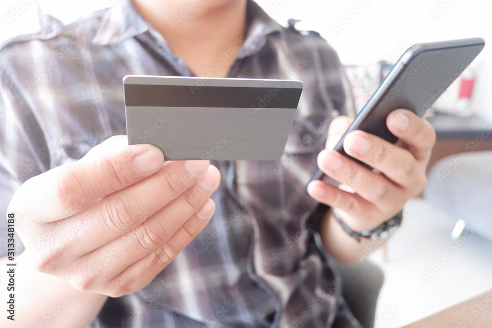 Cropped shot view of woman or man hands holding credit card, typing on laptop computer keyboard for internet banking and payment with phone. Online shopping.