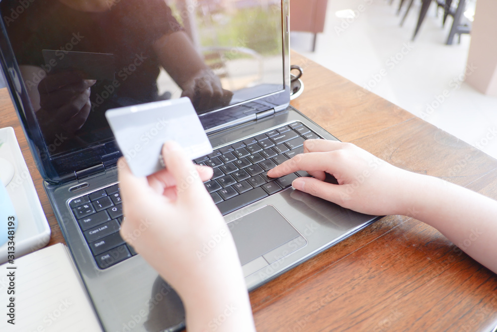 Cropped shot view of woman or man hands holding credit card, typing on laptop computer keyboard for internet banking and payment with phone. Online shopping. Cropped shot view of woman or man hands holding credit card, typing on laptop computer keyboard for internet banking and payment with phone. Online shopping.