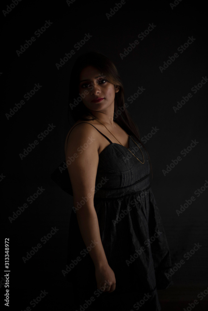 Fashion portrait of an young and attractive Indian Bengali brunette girl with black western dress in front of a black studio background. Indian fashion portrait and lifestyle. Fashion portrait of an young and attractive Indian Bengali brunette girl with black western dress in front of a black studio background. Indian fashion portrait and lifestyle.