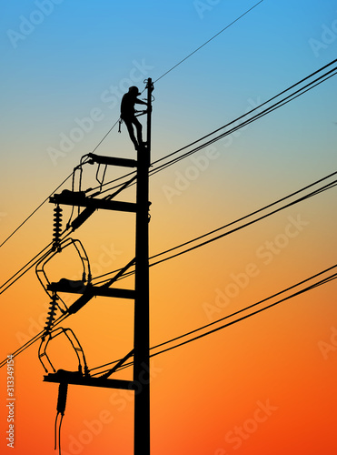 Silhouette Electrical engineers working on electricity pylon high tension power line repairs and maintenance  on blurry sunset background