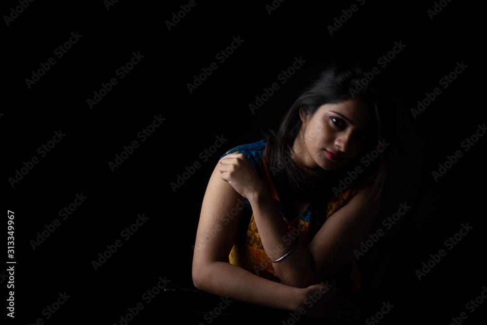 Close up fashion portrait of an young and attractive Indian Bengali brunette girl with colorful western dress in front of a black studio copy space background. Indian fashion portrait and lifestyle. Close up fashion portrait of an young and attractive Indian Bengali brunette girl with colorful western dress in front of a black studio copy space background. Indian fashion portrait and lifestyle.
