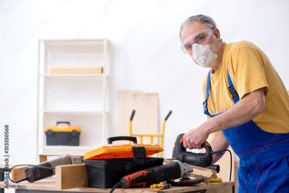 Old male carpenter working in workshop Old male carpenter working in workshop