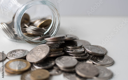 Coins spilled from a jar on white background. Coins in jar