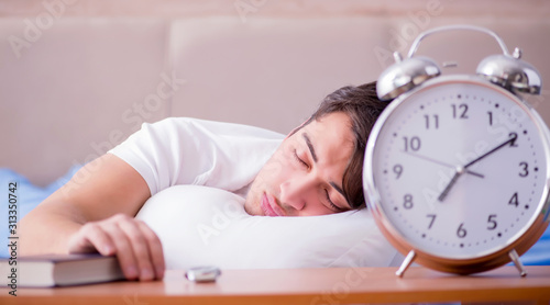 Man in bed frustrated suffering from insomnia with an alarm cloc photo