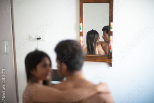 Photography Semi nude couple wrapping with a blanket while sitting on the bed with the upper half of their body exposed in an intimate mood in a winter morning