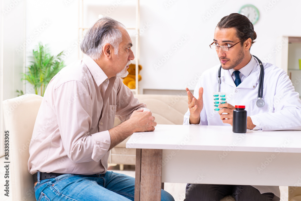 Fototapeta premium Young male doctor visiting old patient at home