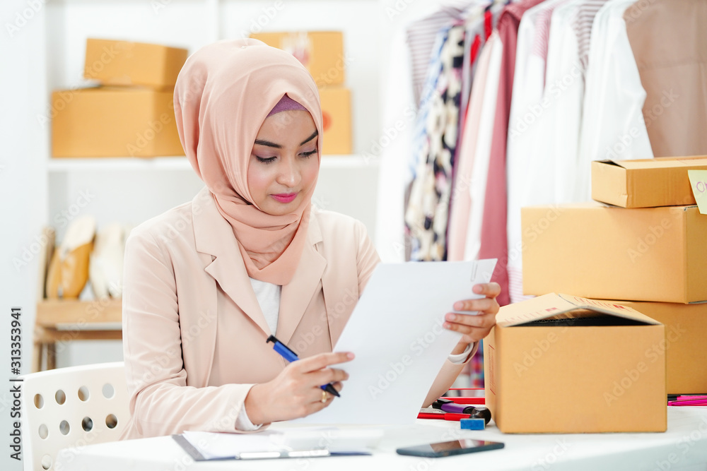 Muslim online business marketing woman is checking the order from the customer. and conducting the packaging process to deliver the product on time. Business online shopping marketing. Muslim online business marketing woman is checking the order from the customer. and conducting the packaging process to deliver the product on time. Business online shopping marketing.