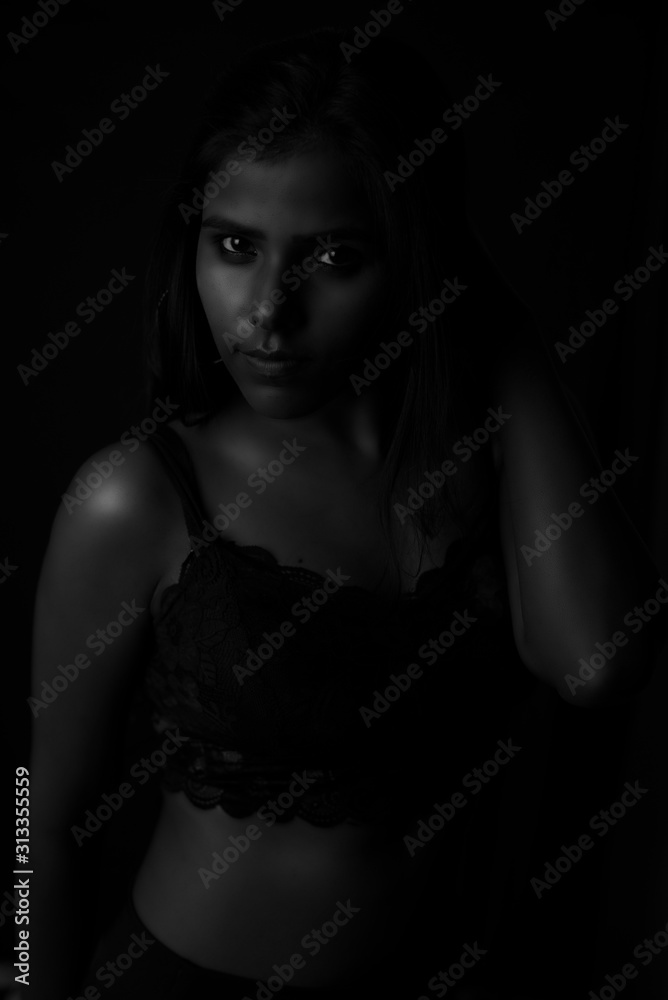Monochrome fashion portrait of an Indian brunette Bengali dark skinned woman with black lingerie standing in black studio copy space background. Indian fashion photography and lifestyle. Monochrome fashion portrait of an Indian brunette Bengali dark skinned woman with black lingerie standing in black studio copy space background. Indian fashion photography and lifestyle.