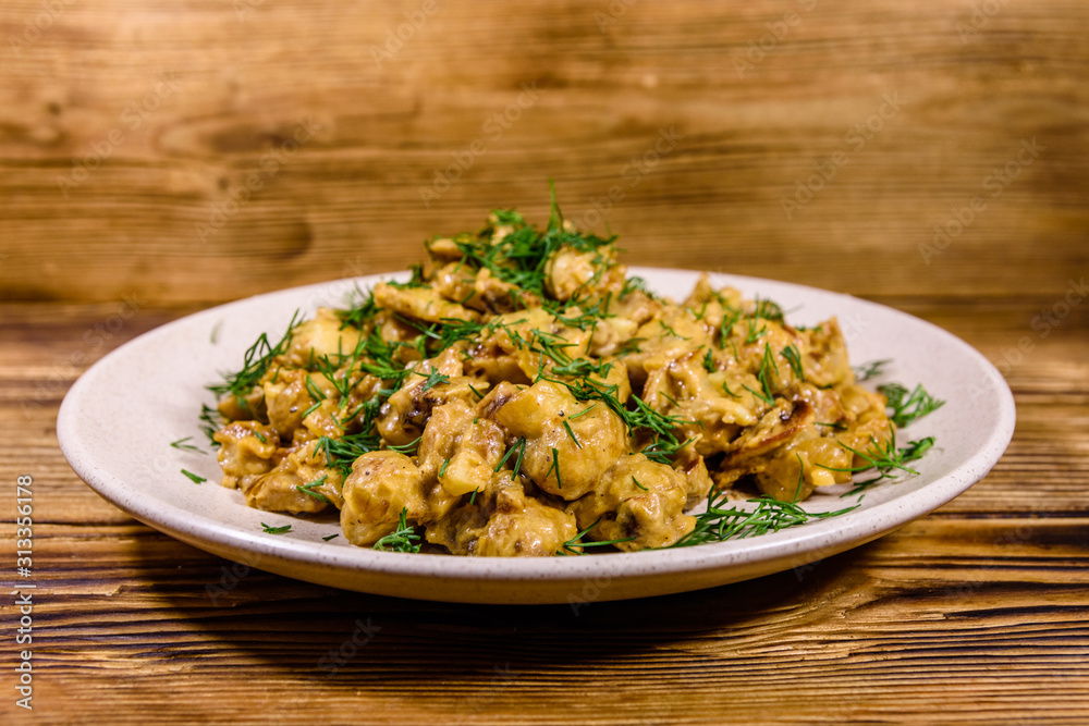 Plate with champignons stewed in sour cream on a wooden table Plate with champignons stewed in sour cream on a wooden table