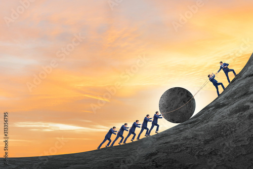 Fototapeta Teamwork example with business people pushing stone to top