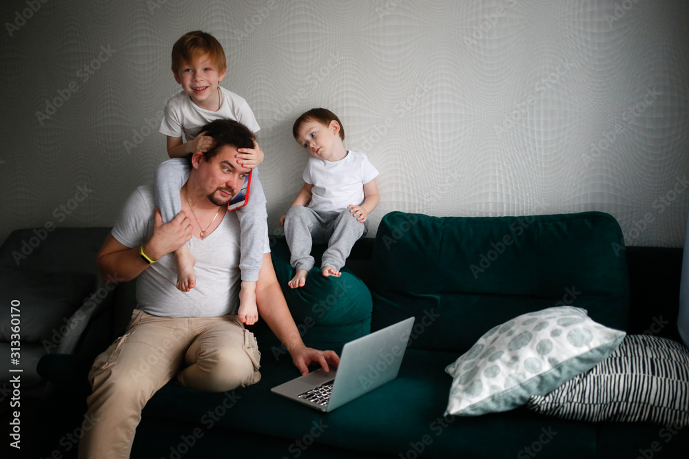 Children around dad working on laptop at home