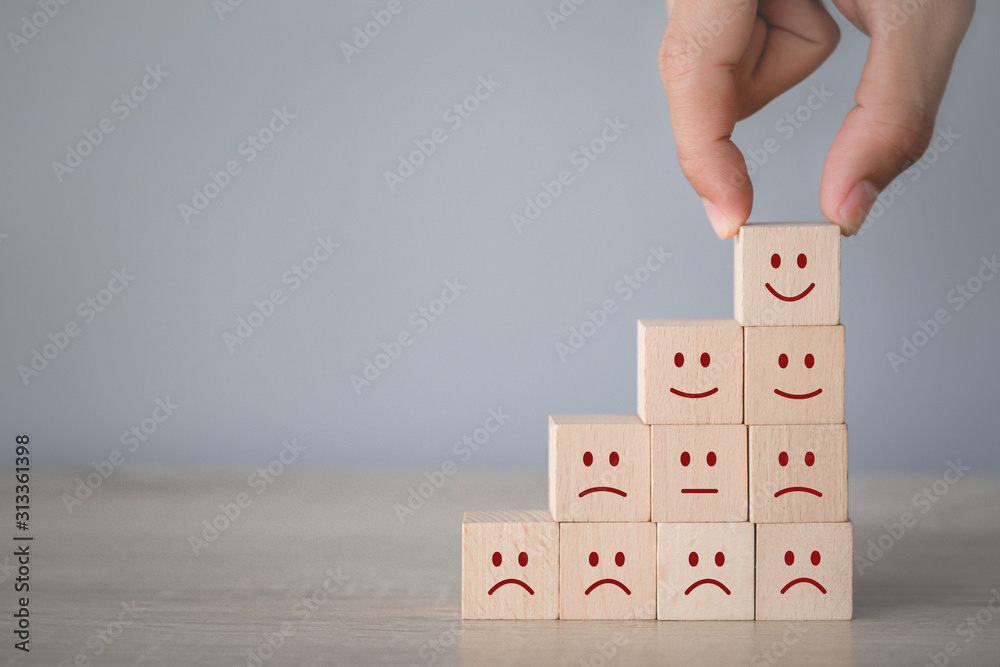 Customer pressing smiley face emoticon on wood cube, Service rating, satisfaction concept. Customer pressing smiley face emoticon on wood cube, Service rating, satisfaction concept.