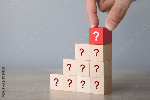 Hand arranging wood block stacking with icon question mark,thinking with question mark concept.