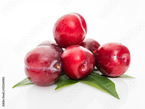 red  plum with green leaves isolated on white background