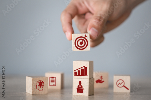 Hand arranging wood block stacking with icon arrow and business,targeting the business concept. photo