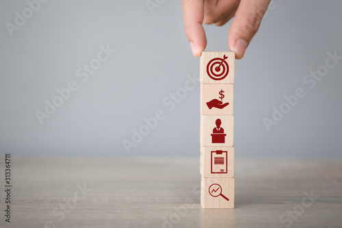 Hand arranging wood block stacking with icon arrow and business,targeting the business concept.