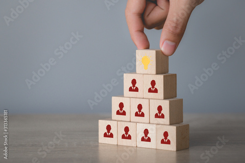 Hand choosing wood cube with icon light bulb and human symbol,creative idea and innovation concept.