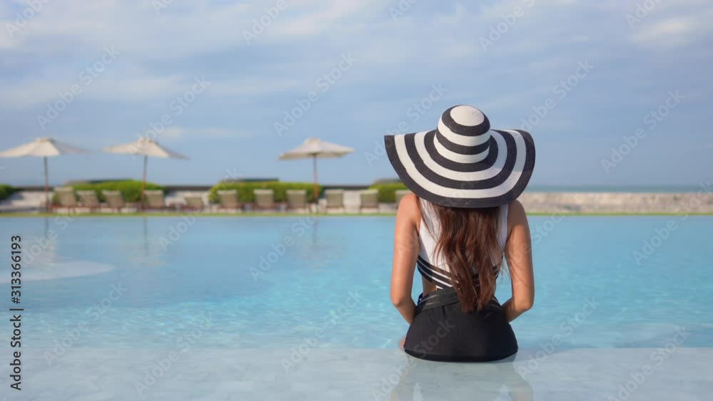 A young woman, with her back to the camera, looks out from the shallow ...