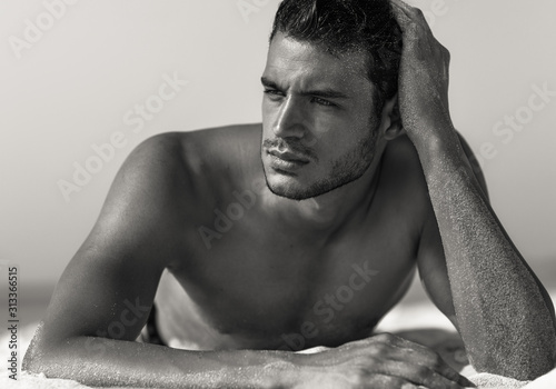 Sexy portrait of handsome topless male model on the beach. Black and White.