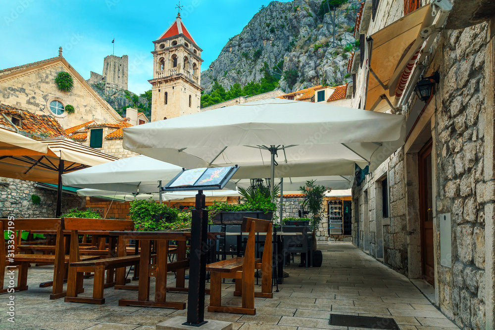 Narrow promenade with cozy street cafe in Omis, Dalmatia, Croatia