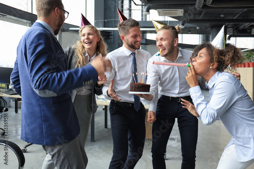 Happy business team with birthday cake are greeting colleague at office party