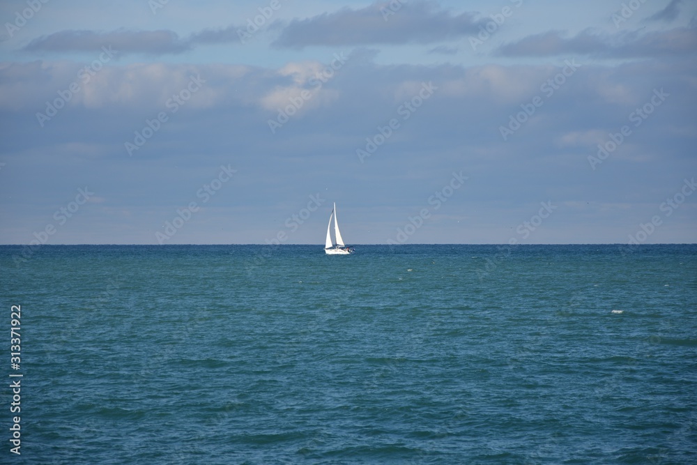 white sailboat in the sea on the horizon