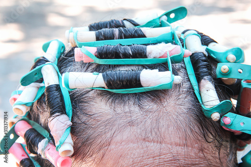 Elderly asian woman head and colorful plastic rollers with hair perm solution , curling process background