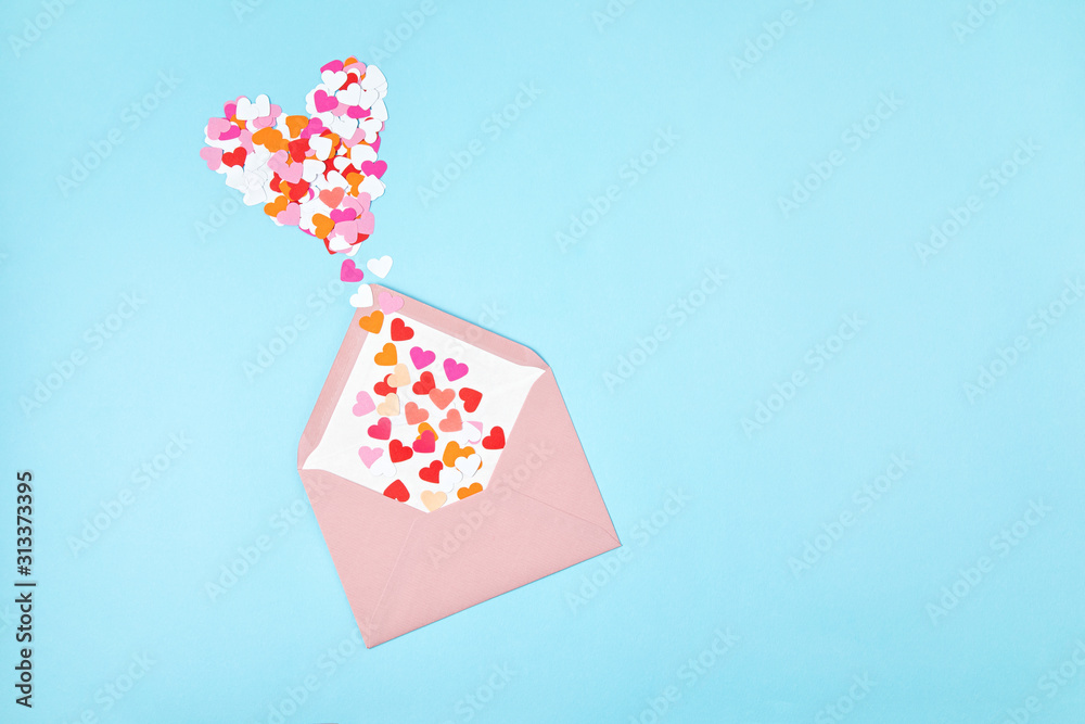 Pink envelope with heart shaped confetti over the blue background. Love, letter, message, saint valentines day concept. Flat lay, top view Pink envelope with heart shaped confetti over the blue background. Love, letter, message, saint valentines day concept. Flat lay, top view