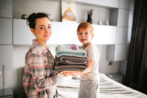 mom and son child with stack of clean towels