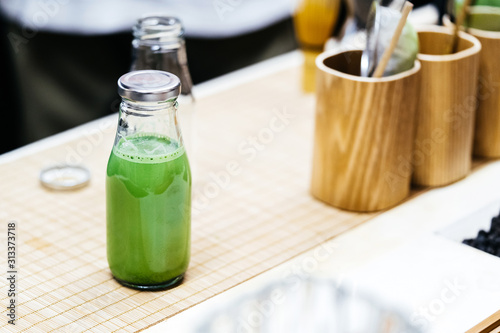 Matcha green tea in a bottle on a wooden table counter in a cafe