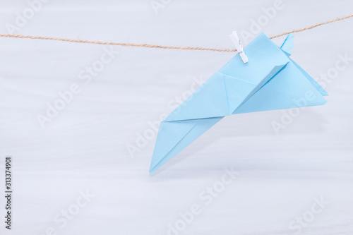 Fear of flying  plane crash or aerophobia concept. Blue paper plane upside down  plane hanging on a thread.