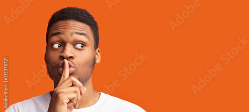 Man making silent gesture with finger on his lips photo