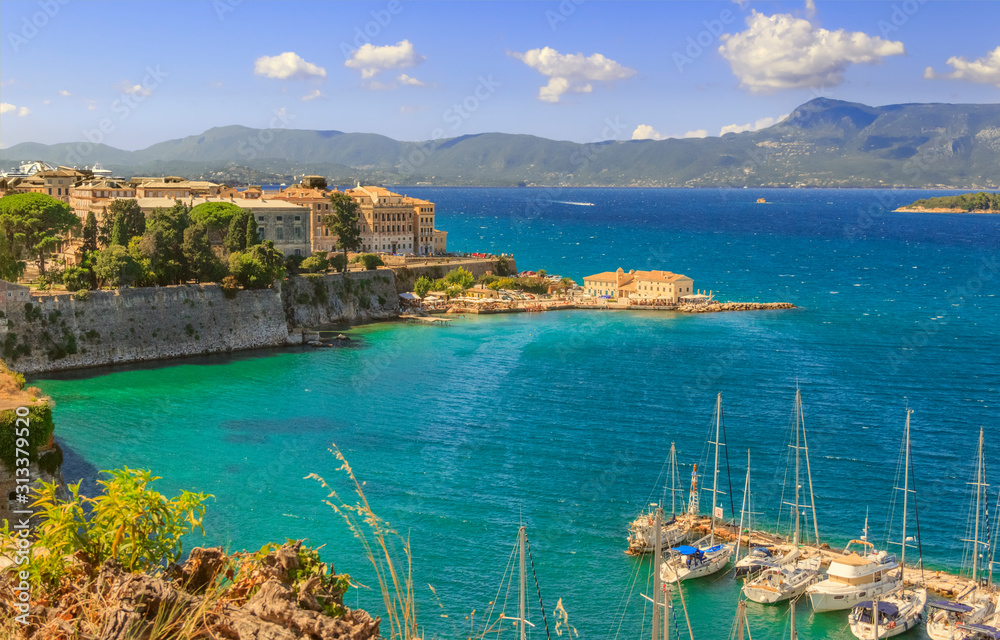 View of the ancient town on peninsula in to the crystal clear azure sea from Old Fortress of Corfu Town. Kerkyra, capital of Corfu island. Greece.