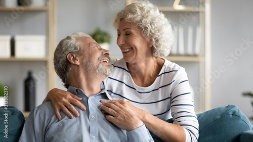 Loving wife hugs beloved grey-haired husband from behind